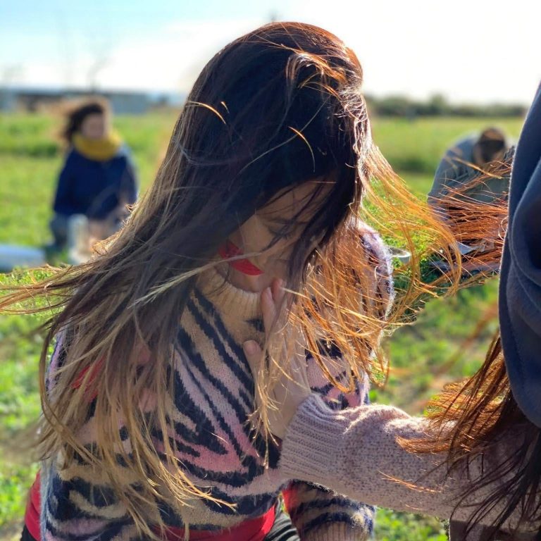 Canalizaciones Conciencia de corazón Una mujer con cabello largo y suelto, agachada en un campo al aire libre.